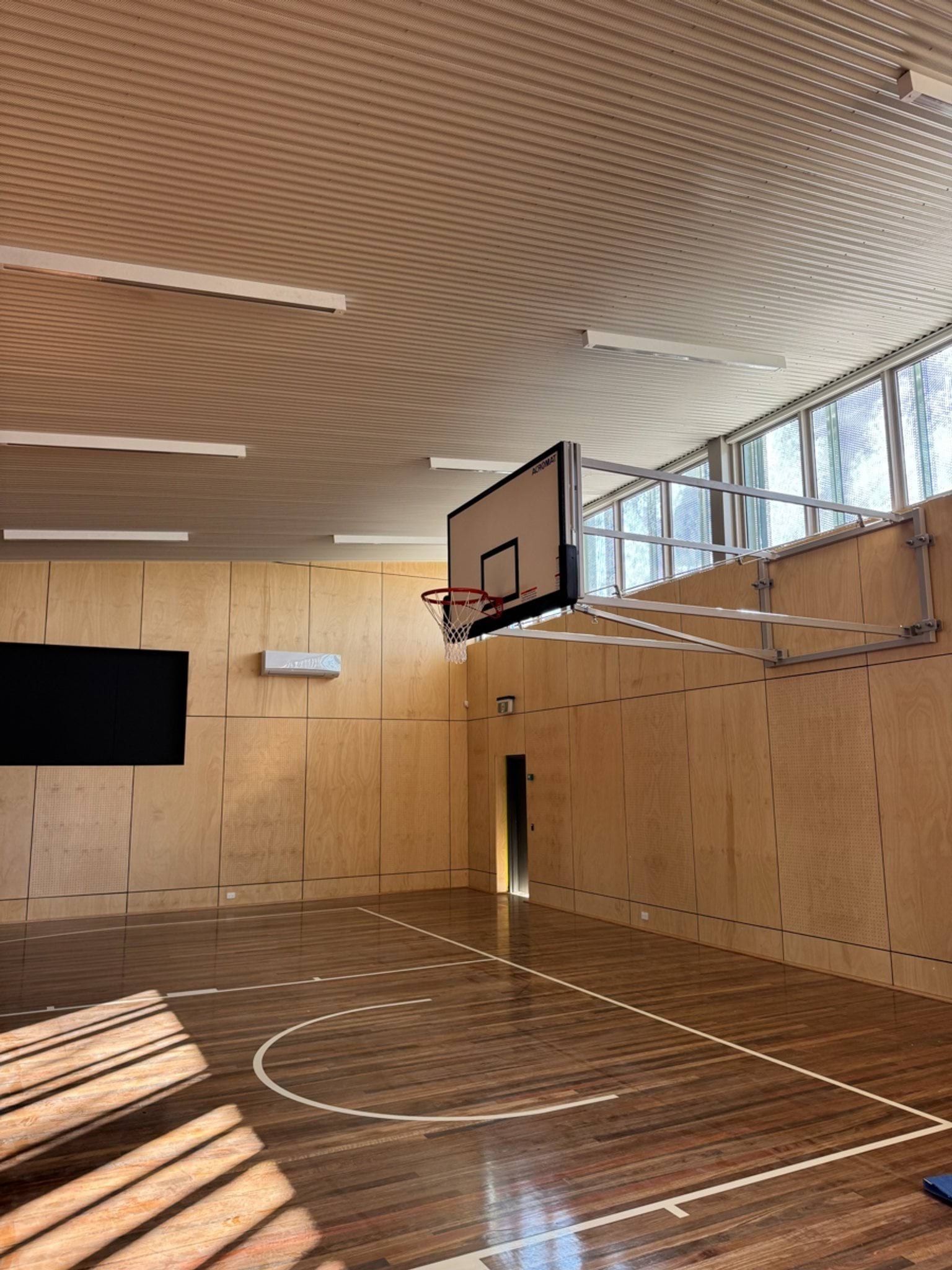 Near-completed indoor sports stadium with a basketball ring and wooden floorboards