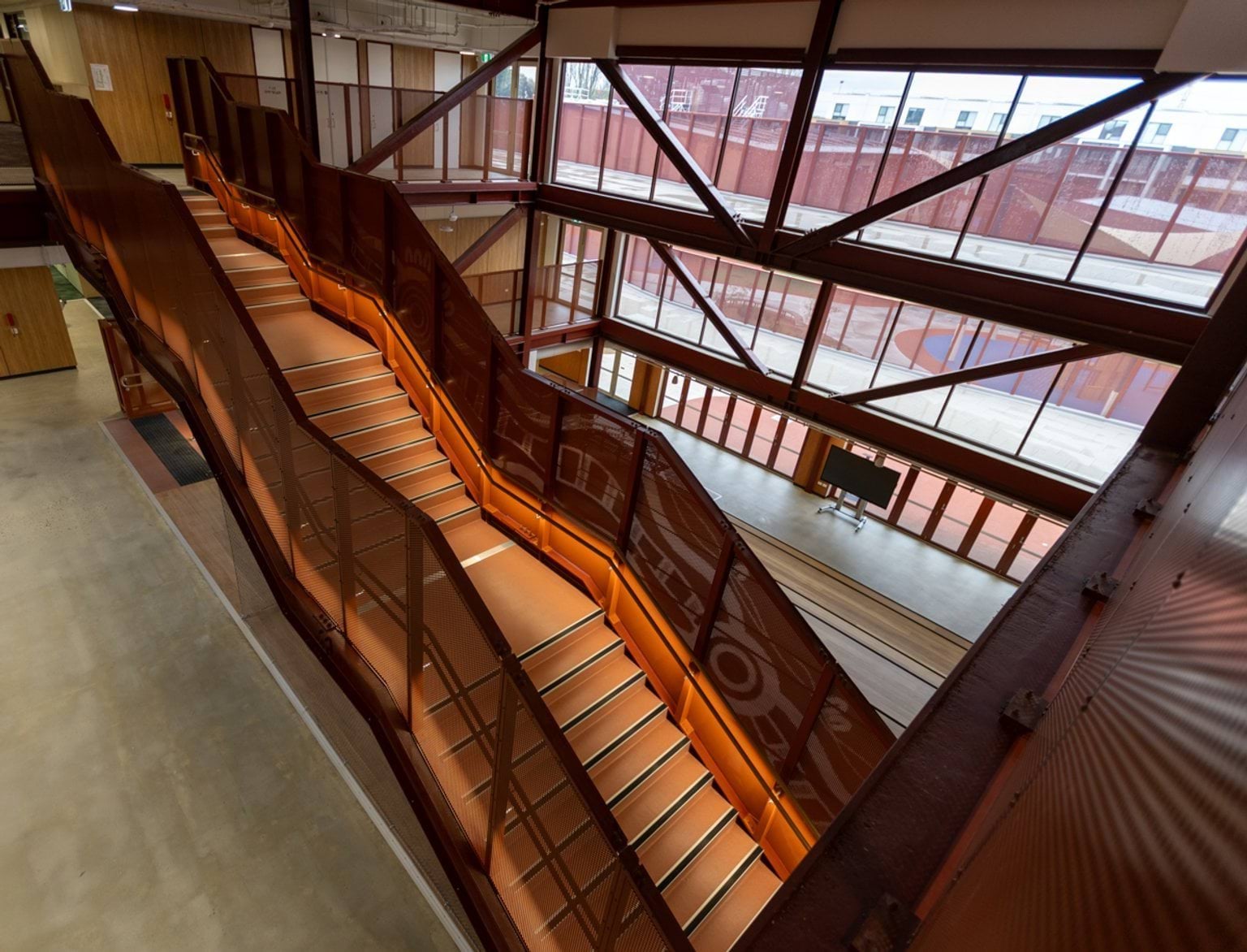 Above view of an open mezzanine area with windows across one side of the building and an open feature stairwell