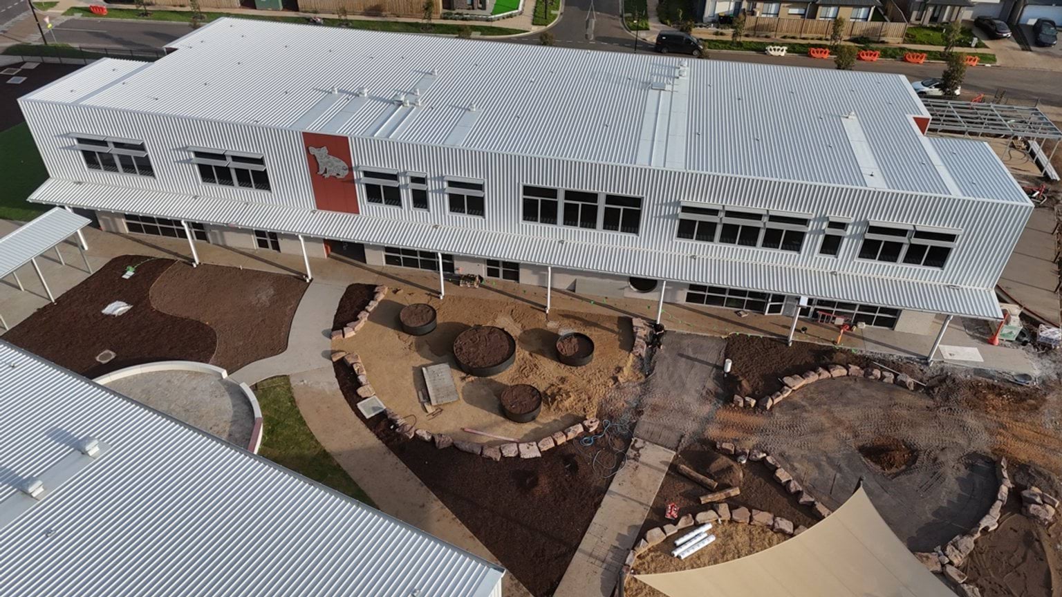 Aerial view of a school courtyard featuring newly landscaped outdoor learning and play spaces between completed buildings.